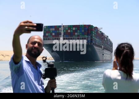 Ismailia, Ägypten. Juli 2021. Menschen fotografieren das jemals gegebene Containerschiff, das auf dem Suezkanal in der Provinz Ismailia, Ägypten, segelt, 7. Juli 2021. Das jemals gegebene Containerschiff, das im März fast eine Woche lang den Suezkanal blockierte, begann am Mittwoch seine Reise aus dem Kanal, sagte Osama Rabie, Vorsitzender der Suezkanal-Behörde (SCA). Die SCA hat das Riesenschiff in einem See zwischen zwei Teilen der Wasserstraße gehalten, seit es am 29. März wieder in Umlauf gebracht wurde, da der Streit über die beantragte Entschädigung durch die SCA nicht beigelegt wurde. Quelle: Ahmed Gomaa/Xinhua/Alamy Live News Stockfoto