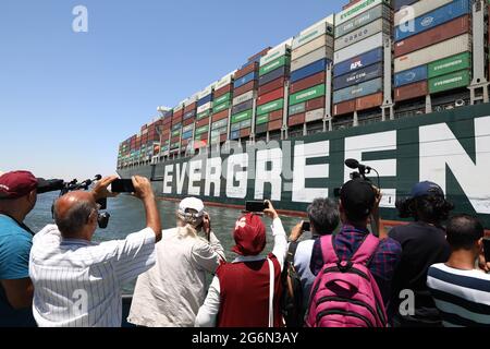 Ismailia, Ägypten. Juli 2021. Menschen fotografieren das jemals gegebene Containerschiff, das auf dem Suezkanal in der Provinz Ismailia, Ägypten, segelt, 7. Juli 2021. Das jemals gegebene Containerschiff, das im März fast eine Woche lang den Suezkanal blockierte, begann am Mittwoch seine Reise aus dem Kanal, sagte Osama Rabie, Vorsitzender der Suezkanal-Behörde (SCA). Die SCA hat das Riesenschiff in einem See zwischen zwei Teilen der Wasserstraße gehalten, seit es am 29. März wieder in Umlauf gebracht wurde, da der Streit über die beantragte Entschädigung durch die SCA nicht beigelegt wurde. Quelle: Ahmed Gomaa/Xinhua/Alamy Live News Stockfoto