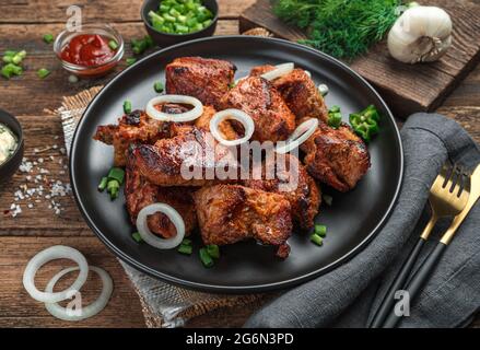 Gebratenes Fleisch mit Kräutern und Zwiebeln aus der Nähe auf einem Holzhintergrund. Seitenansicht, Nahaufnahme. Stockfoto