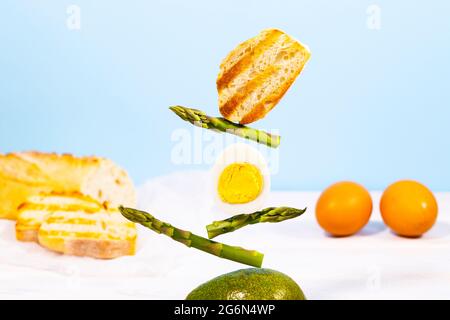 Frisches Brot, Spargel, Avocado und Ei. Zum Frühstück gibt es Inridients. Gleichgewichtsschwimmende Lebensmittel. Balance Levitation Food. Stockfoto