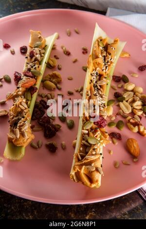 Gesunde Snack Erdnussbutter Sellerie oder Ameisen auf einem Log mit gemischten Nüssen und Samen Stockfoto