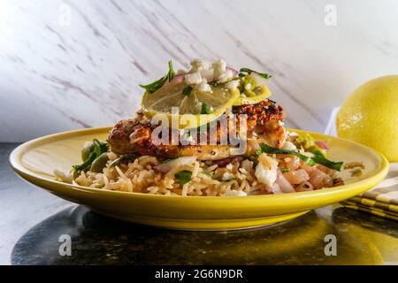 Griechische Haut-on Knochen-in knusprige Hähnchenschenkel mit Reis und castelvetrano Oliven mit Feta-Käse serviert Stockfoto