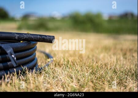 Spule von 1 Zoll Bewässerungsschlauch bereit für die neue Installation auf der Oberseite von braunen und beschädigten trockenen Gras. Stockfoto