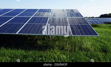 Sonnenlichtreflexion aus nächster Nähe auf Solarenergie Photovoltaik PV-Panels über dem Gras mit Naturhintergrund installiert. Stockfoto