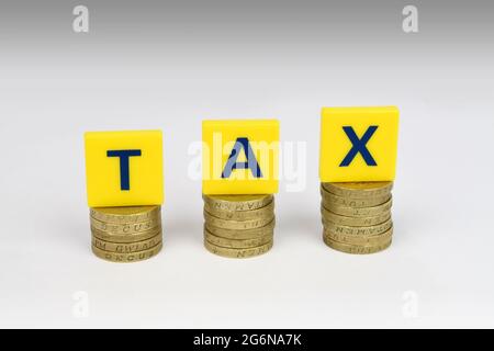 Drei Stapel von Münzen mit Buchstaben Schreibsteuer auf ihnen. Eine finanzielle Metapher für die zunehmende Belastung durch Steuern. Stockfoto