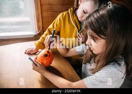 Niedliche Kinder Geschwister malen den halloween Kürbis zu Hause. Authentisches Leben. Stockfoto