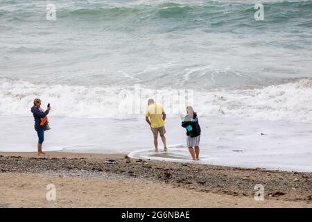 Portreath,Cornwall,7. Juli 2021,Trotz des grauen und trostlosen Wetters waren einige Leute bei Flut am Strand in Portreath, Cornwall. Surfer machten das Beste aus den großen Wellen, da das Wetter voraussichtlich 17C sonnige Intervalle mit einer leichten Brise später an diesem Abend sein wird.Quelle: Keith Larby/Alamy Live News Stockfoto