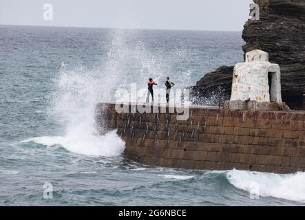 Portreath,Cornwall,7. Juli 2021,zwei Teenager stehen bei Flut in Portreath, Cornwall, gefährlich auf der Meeresmauer. Dies ist ein gefährlicher Ort, da oft extrem hohe Wellen darüber krachen, die eine Person ins Meer stoßen können. Kredit: Keith Larby/Alamy Live Nachrichten Stockfoto