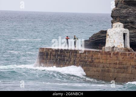 Portreath,Cornwall,7. Juli 2021,zwei Teenager stehen bei Flut in Portreath, Cornwall, gefährlich auf der Meeresmauer. Dies ist ein gefährlicher Ort, da oft extrem hohe Wellen darüber krachen, die eine Person ins Meer stoßen können. Kredit: Keith Larby/Alamy Live Nachrichten Stockfoto