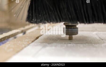 Nahaufnahme - Fräsen auf einer CNC-Maschine. Schneidet lockige Stücke aus Acrylglas. Sägemehl streut in verschiedene Richtungen, Schutzbürste. Gravierproz Stockfoto