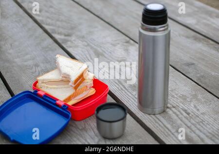 Picknickblick mit frisch zubereitetem Weißbrot und Käse-Sandwich. Reisetasse aus Edelstahl, sonniger Herbsttag Stockfoto