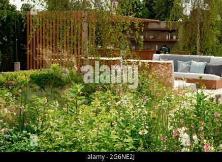 Eine gemischte Grenze neben einem Sitzbereich und einer Außenküche im Viking Friluftsliv Garden beim Hampton Court Palace Garden Festival 2021 Stockfoto