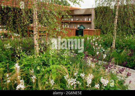 Eine gemischte Grenze aus blühenden Pflanzen und eine Außenküche im Viking Friluftsliv Garden beim Hampton Court Palace Garden Festival 2021 Stockfoto