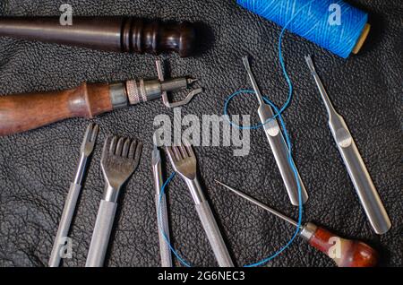 Echtes Leder. Eine Handtasche nähen. Lederarbeiten. Werkzeuge zum Nähen von Geldbörsen, Kupplungen. Manuelles Nähen des Produkts. Die Herstellung von Lederprodukten. Stockfoto