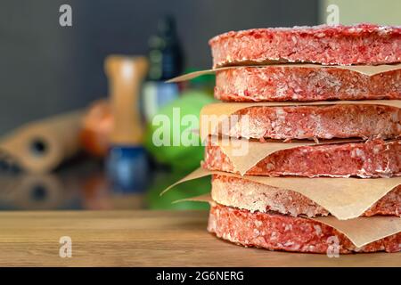 Gefrorene Hamburger-Hacksteaks, vor dem Bratvorgang auftauen, auf der Theke gestapelt. Stockfoto