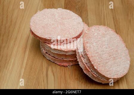 Gefrorene Hamburger-Hacksteaks, vor dem Bratvorgang auftauen, auf der Theke gestapelt. Stockfoto