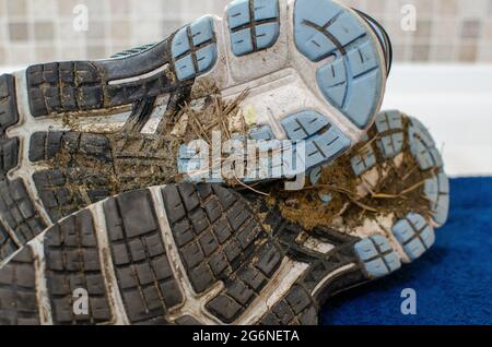 Schmutzige Außensohle nach dem Laufen. Schmutzige Sneakers putzen.ein Paar Sneakers mit schmutzigen Sohlen liegt vor dem Reinigen auf einem blauen Handtuch Stockfoto