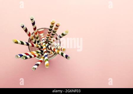 Trinkhalm. Farbige Cocktailröhrchen aus Papier auf einem rosa Hintergrund. In einer Glasschale. Blick von oben, Nahaufnahme. Platz für Text Stockfoto