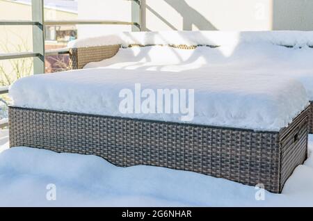 Nahaufnahme von verschneiten synthetischen Kunststoff Rattan und Glas Gartenmöbel an einem kalten Wintertag. Gartenmöbelpflege-Konzept. Stockfoto