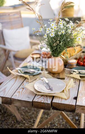 Wunderschön servierte Holztische mit Speisen und Gerichten im natürlichen Boho-Stil im Freien Stockfoto