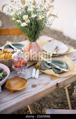 Wunderschön servierte Holztische mit Speisen und Gerichten im natürlichen Boho-Stil im Freien Stockfoto