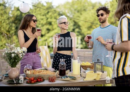 Junge, stilvolle Freunde bei einem festlichen Abendessen auf der Dachterrasse Stockfoto