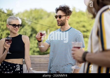 Junge, stilvolle Freunde bei einem festlichen Abendessen auf der Dachterrasse Stockfoto