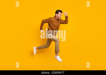 In voller Größe Profilfoto des optimistischen schönen Brunet Mann Run tragen Pullover auf gelbem Hintergrund isoliert Stockfoto