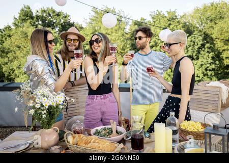 Junge, stilvolle Freunde bei einem festlichen Abendessen auf der Dachterrasse Stockfoto