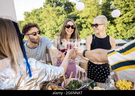 Junge, stilvolle Freunde bei einem festlichen Abendessen auf der Dachterrasse Stockfoto