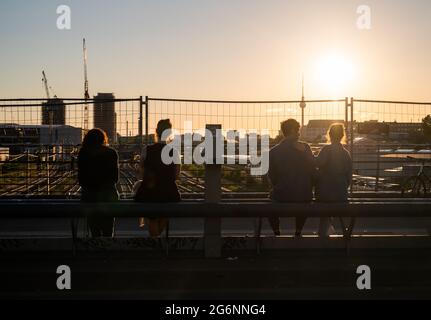 Berlin, Deutschland. Juli 2021. Menschen, die auf der Modersohn-Brücke sitzen, wenn die Sonne untergeht. Quelle: Christophe Gateau/dpa/Alamy Live News Stockfoto