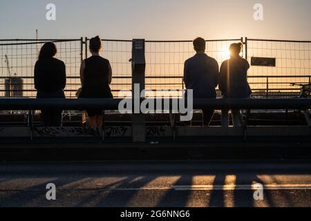 Berlin, Deutschland. Juli 2021. Menschen, die auf der Modersohn-Brücke sitzen, wenn die Sonne untergeht. Quelle: Christophe Gateau/dpa/Alamy Live News Stockfoto