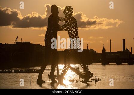 Berlin, Deutschland. Juli 2021. Paddelboote fahren unter der Skulptur 'Molecule man' des amerikanischen Bildhauers Jonathan Borofsky vorbei, während die Sonne auf der Spree untergeht. Quelle: Christophe Gateau/dpa/Alamy Live News Stockfoto