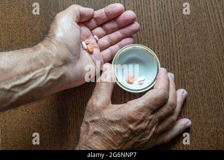 Ein älterer Mann bereitete alle Tabletten für eine Dosis in einer kleinen Tasse zu Stockfoto