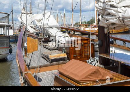 Alte Holzjachten, die in der Marina am Meer festgemacht sind. Holzdeck eines Segelschiffes und Mast, Segel aufgerollt. Stockfoto