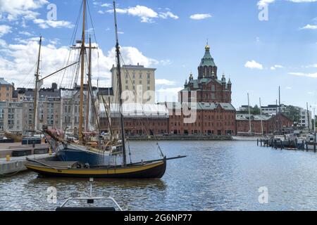 Hölzerne Segelboote, die im alten Hafen in Helsinki, Finnland, festgemacht sind. Im Hintergrund orthodoxe Uspenski Kathedrale und Kai. Stockfoto