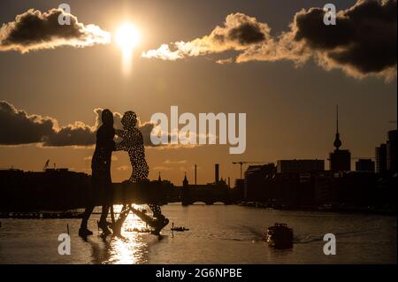 Berlin, Deutschland. Juli 2021. Paddelboote fahren unter der Skulptur 'Molecule man' des amerikanischen Bildhauers Jonathan Borofsky vorbei, während die Sonne auf der Spree untergeht. Quelle: Christophe Gateau/dpa/Alamy Live News Stockfoto