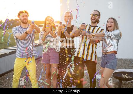 Junge, stilvolle Freunde feiern auf dem Dach bei Sonnenuntergang Stockfoto