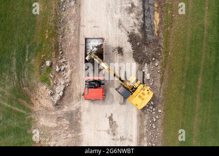 Bagger graben Boden in der Nähe des Feldes und Verladung auf den LKW Stockfoto