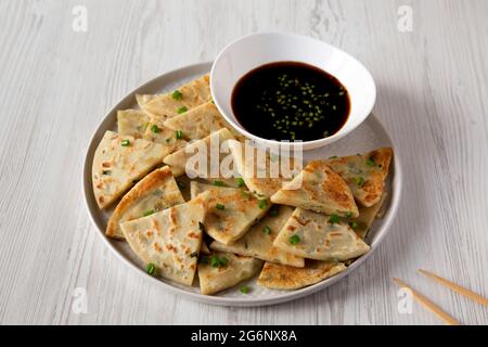 Hausgemachte Scallion Pancakes mit Soja-Dipping-Sauce auf weißem Holzhintergrund, Seitenansicht. Stockfoto