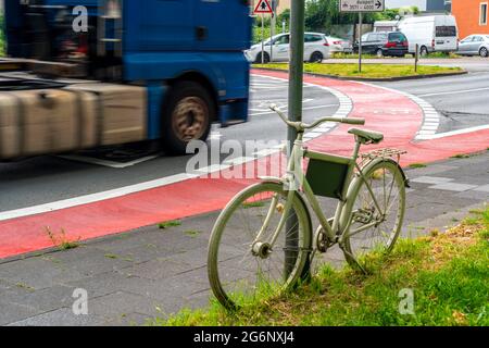 Weißes Fahrrad erinnert an einen tödlichen Unfall mit einem Radfahrer, rote Radweg markiert in einem innerstädtischen Kreisverkehr, um Fahrer darauf aufmerksam zu machen, dass auch Radfahrer Stockfoto