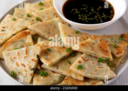 Hausgemachte Scallion Pancakes mit Soja-Dipping-Sauce auf weißem Holzhintergrund, Seitenansicht. Nahaufnahme. Stockfoto