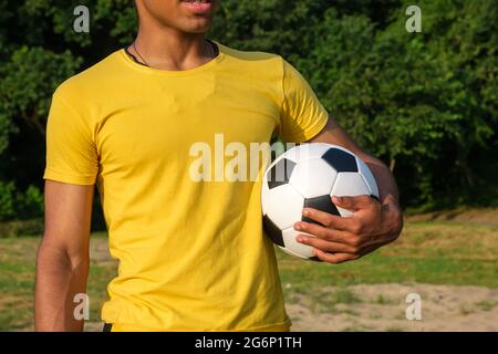 Afroamerikanischer Mann hält Fußball, während er im Park im Freien steht Stockfoto