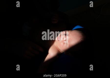 Ein neugeborenes Baby in einem Lichtstiel Stockfoto