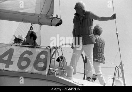 AJAXNETPHOTO. JULI 1979. SOLENT, COWES, ENGLAND. - KEEPING LOOKOUT - EDWARD HEATH STANDING LOOKOUT IN DER STERNSHEETS SEINER YACHT MORNING CLOUD AM START DES COWES - DINARD OFFSHORE-RENNENS. FOTO: JONATHAN EASTLAND/AJAX REF:2790707 23 13 Stockfoto