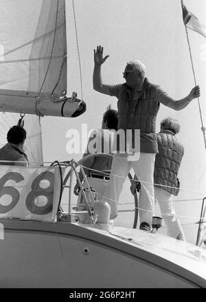 AJAXNETPHOTO. JULI 1979. SOLENT, COWES, ENGLAND. - WACHPOSTEN - EDWARD HEATH STANDING LOOKOUT IN DER STERNSHEETS SEINER YACHT MORNING CLOUD AM START DES COWES - DINARD OFFSHORE-RENNENS WINKT DEN ZUSCHAUERN ZU. FOTO: JONATHAN EASTLAND/AJAX REF:2790707 18 18 Stockfoto