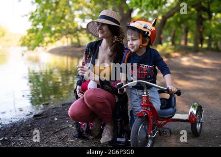 Eine Mutter mit ihrem Kind auf einem Dreirad in einem Park Stockfoto