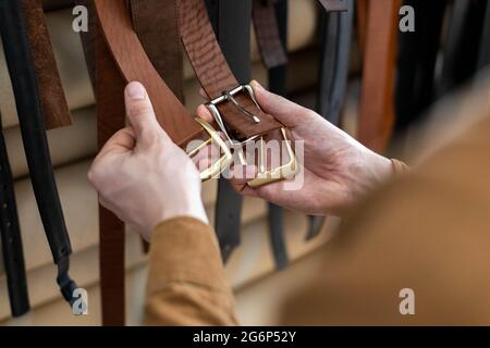 Nahaufnahme Hände von professionellen Gerber Wahl Gürtelschnalle auf Holztisch in Leder-Werkstatt Stockfoto