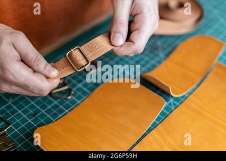 Prozess Schneidschema von Beutel mit Geräten und Materialien. Männlicher Gerber, der in der Lederwerkstatt arbeitet Stockfoto