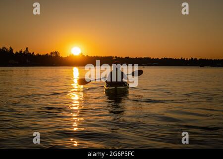 Mädchen Kajakfahren und Pause ruhiges Meer um Mitternacht in Nordschweden während der leichten Sommernächte. Den ganzen Tag rund um die Sonne in Polarregionen. Stockfoto